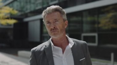 Dışarıda poz veren şık takım elbiseli başarılı bir yaşlı adam.