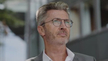 Dışarıdaki kameraya bakan kendine güvenen yaşlı bir adam.