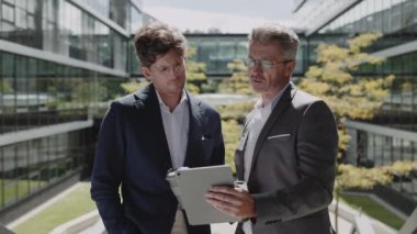 İş ortakları kahve içiyor ve sokakta tablet kullanıyor.