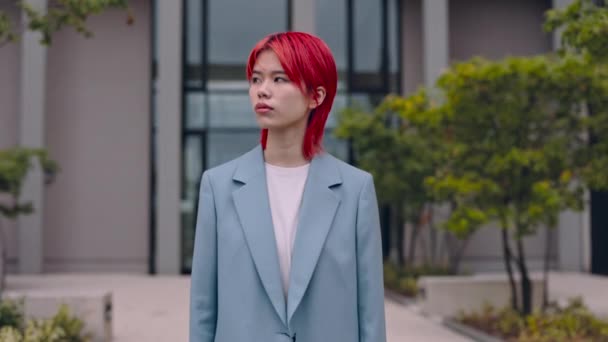 Retrato de mujer de negocios asiática con el pelo rojo mirando una cámara con confianza en los ojos mientras está de pie en la calle de la ciudad. Concepto de personas, individualidad y estilos de vida — Vídeos de Stock