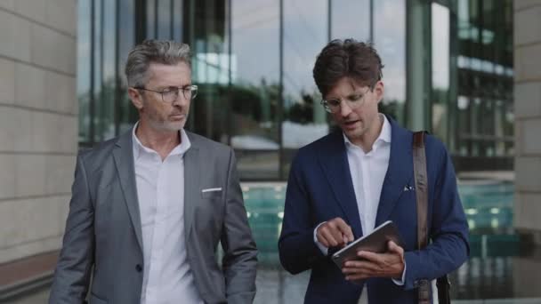 Businessmen talking and looking on tablet outdoors — Vídeo de Stock