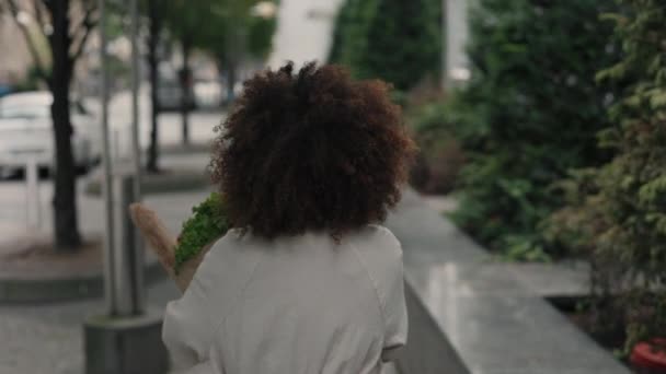 Visão traseira da senhora andando na rua e levando saco de supermercado — Vídeo de Stock