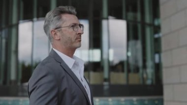 Sokakta duran şık takım elbiseli, gülümseyen bir işadamı.