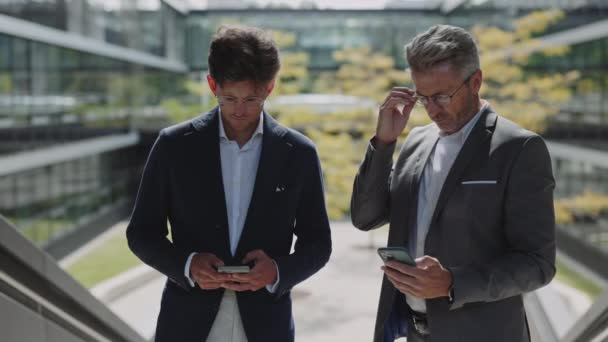 Dva obchodní kolegové pomocí chytrých telefonů v městské oblasti — Stock video