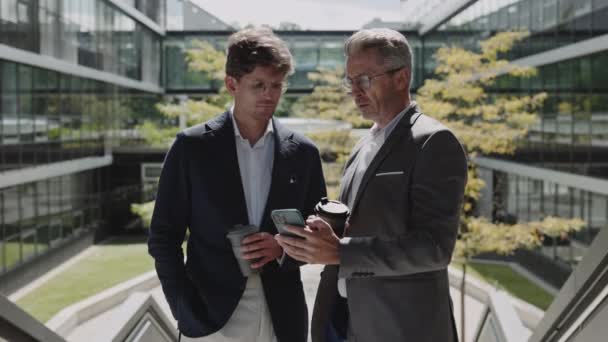 Hommes d'affaires debout dans la rue avec café et mobile — Video