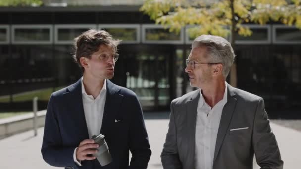 Δύο υπάλληλοι γραφείου μιλούν και περπατούν με τον καφέ έξω — Αρχείο Βίντεο