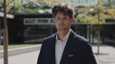 İş adamı, kameraya sakin bir şekilde bakıyor.