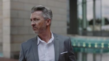 Açık havada poz veren başarılı, resmi kıyafetli yaşlı bir adam.