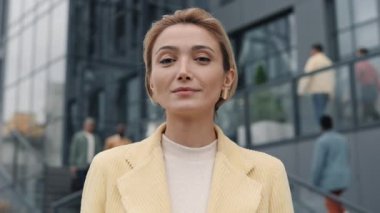 İş kadını gülümsüyor ve caddede kameraya bakıyor.