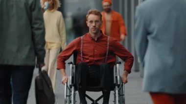 Kalabalık şehir sokaklarında tekerlekli sandalyedeki genç adam