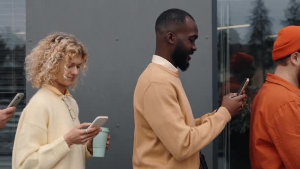 Multiculturális emberek sorban állnak és mobiltelefonokat használnak — Stock videók