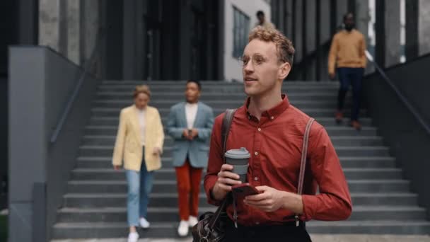 Hombre caminando cerca del centro de oficinas con móvil y café — Vídeo de stock
