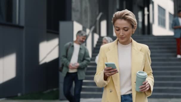 Resmi olarak kahve taşıyan ve cep telefonu kullanan bir kadın. — Stok video