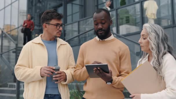 Three diverse people talking outdoors near office center — Vídeo de Stock