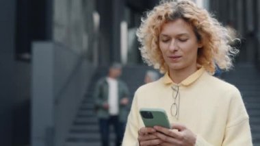 Woman with mobile in hands walking near office center