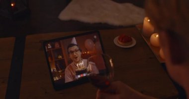 Two gays celebrating birthday online with cake and wine