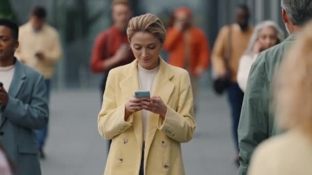 Ділова леді ходить по зайнятій вулиці і використовує мобільний — стокове відео