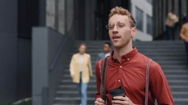 Man with coffee and bag walking near office center — Stok video