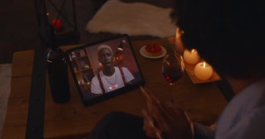 African couple drinking wine and chatting during video call