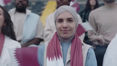 Muslim woman in hijab watching football game on stadium