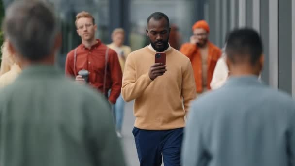 Afrikai amerikai férfi sétál az utcán, és használja a mobil — Stock videók