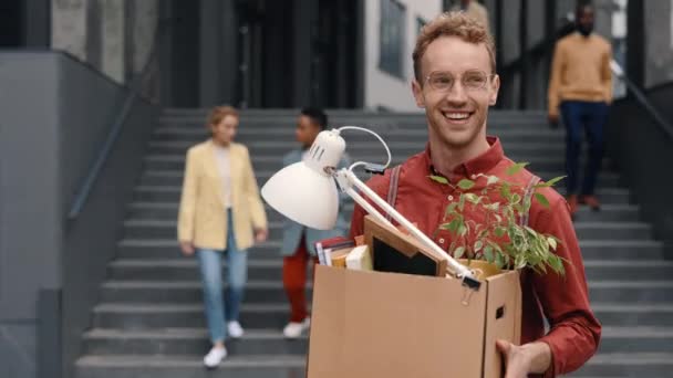 Ευτυχισμένος άνθρωπος μεταφέρουν κουτί με τα πράγματα του γραφείου σε εξωτερικούς χώρους — Αρχείο Βίντεο