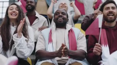 Positive fan clapping and smiling while watching soccer game