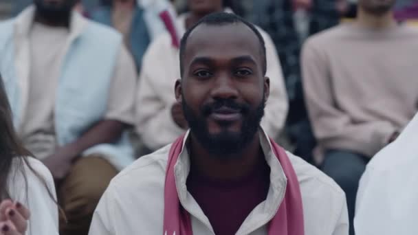 African american man watching football match from bleachers — Stockvideo