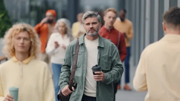 Successful grey haired man walking on busy urban street — Video Stock