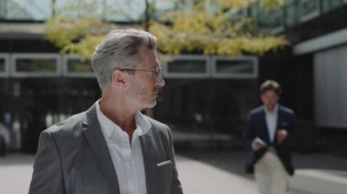 Businessman signing papers that holding male assistant