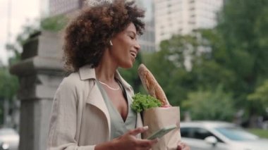 Bakkal çantası taşıyan ve sokakta müzik dinleyen bir kadın.