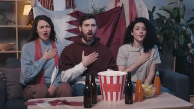 Kendine güveni tam, heyecanlı genç melez arkadaşlar evde TV karşısında oturup maç izlemeden önce vatansever ilahiler söylüyorlar. Sevindiler, alkışladılar..