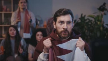 Spor takımı için tezahürat yapan sakallı bir adam TV 'de program maçı izlerken olumlu sonuçlar almayı umuyor. Gergin adam maçta kaybettiği için hayal kırıklığı yaşıyor..