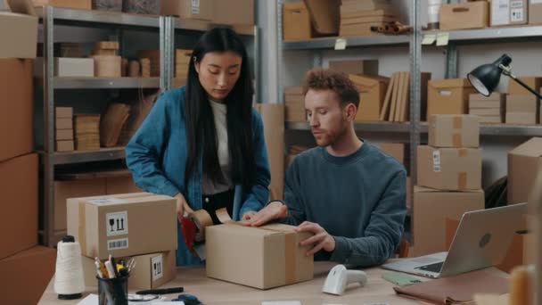 Propriétaires. Les jeunes employés de l'entrepôt scellent les colis avec du ruban adhésif, tout en préparant la boîte de livraison au bureau à domicile. Service postal et concept de petite entreprise, — Video