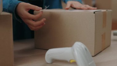 Pakette çalışırken barkodla yapıştırma yapıştıran Asyalı kadının kırpılmış görüntüsü. Posta servisi ve küçük işletme kavramı.