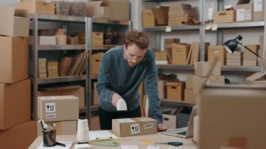 Kızıl Kafkasyalı adam ambalajları tarıyor ve depoda tek başına çalışırken raflara koyuyor. Posta servisi ve küçük işletme kavramı.