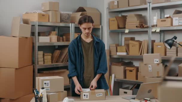 Dükkan sahibi. Kafkasyalı esmer adam depoda çalışırken paketin üzerine müşteri adresi etiketleri yapıştırıyor. Posta servisi ve küçük işletme kavramı. — Stok video