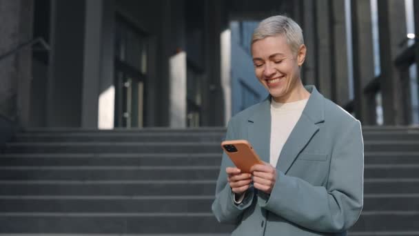 Mulher madura de pé perto do centro de escritório e usando móvel — Vídeo de Stock