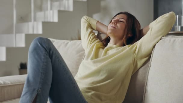 Mujer relajada sentada en un cómodo sofá con los ojos cerrados — Vídeo de stock