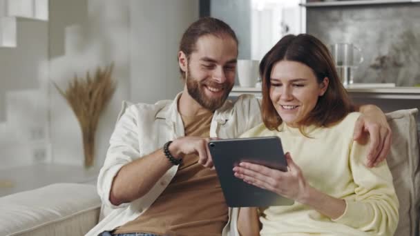 Mężczyzna i kobieta stosujący tabletkę podczas odpoczynku na kanapie — Wideo stockowe