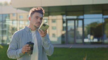 Ofis binasının yanındaki cep telefonundan sesli mesaj kaydeden adam.