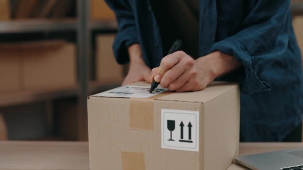 Depoda çalışırken büyük dolap kutusuna bir şeyler yazan adamın görüntüsü kesilmiş. Posta servisi ve küçük işletme kavramı. — Stok video