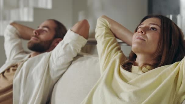 Dva milující lidé odpočívají na gauči s rukama za hlavou — Stock video