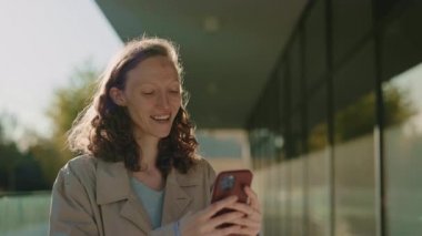 Şehir merkezinde akıllı telefon kullanan mutlu genç bayan.