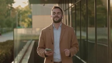 Açık havada kulaklıkla müzik dinleyen mutlu iş adamı.