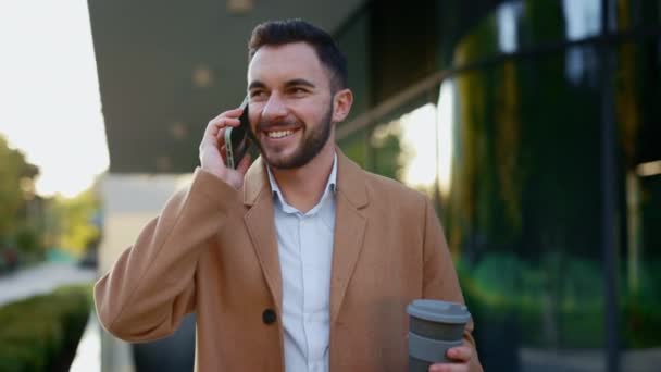 Affärsman talar i mobilen medan du går med kaffe — Stockvideo