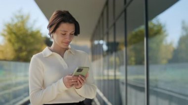 Şehir merkezinde modern akıllı telefon kullanan hoş bir kadın.