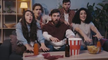 Çok ırklı bir grup mutlu arkadaş birlikte eğleniyor ve TV karşısında el sallıyorlar. Gençler evde maç izlerken takımı destekliyor. Boş zaman kavramı..