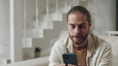 Şaşkın adam evde akıllı telefondan harika haberler alıyor.