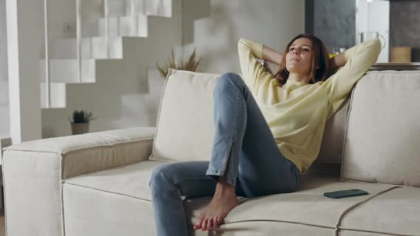 Happy woman in casual wear resting on sofa at home — Stock Video